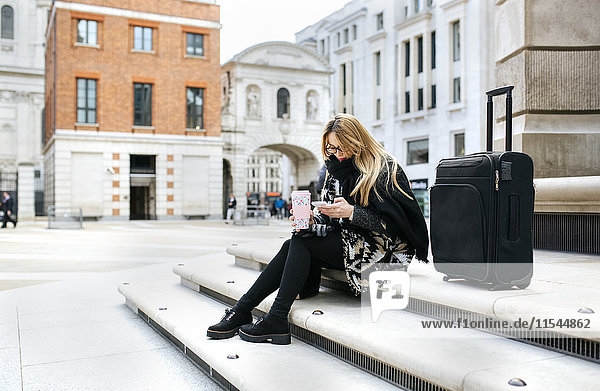 UK  London  junge Frau mit Gepäck beim Telefonieren auf der Treppe