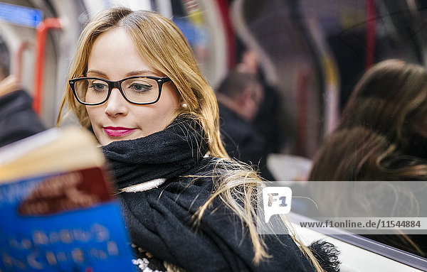 Junge Frau beim Lesen in der U-Bahn