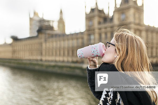 UK  London  junge Frau trinkt Kaffee vor dem Palace of Westminster