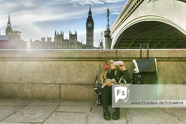 UK  London  young woman listening music near Westminster Bridge