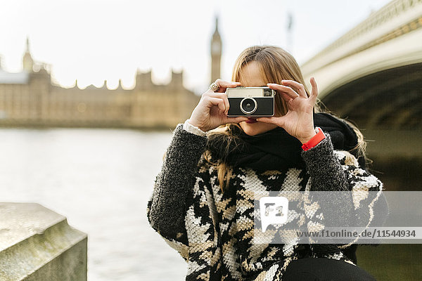UK  London  junge Frau beim Fotografieren nahe der Westminster Bridge