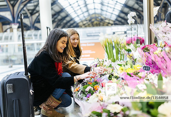UK  London  Two young women admiring flowers at train station