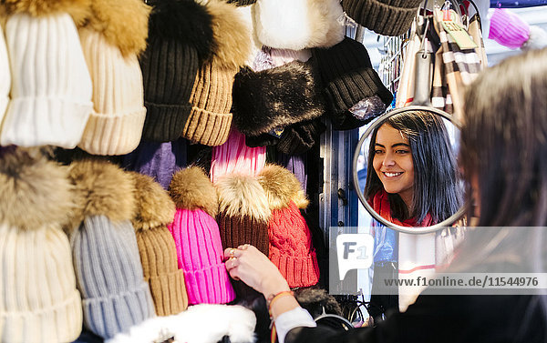 Young woman choosing wooly hat at stall