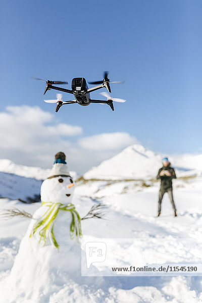 Spanien  Asturien  Mann fliegt Drohne in schneebedeckten Bergen
