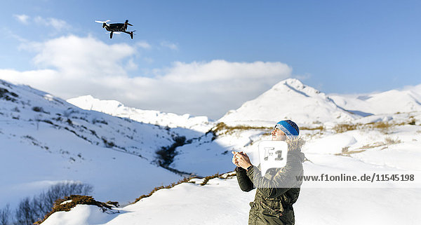 Spain  Asturias  man flying drone in snowy mountains