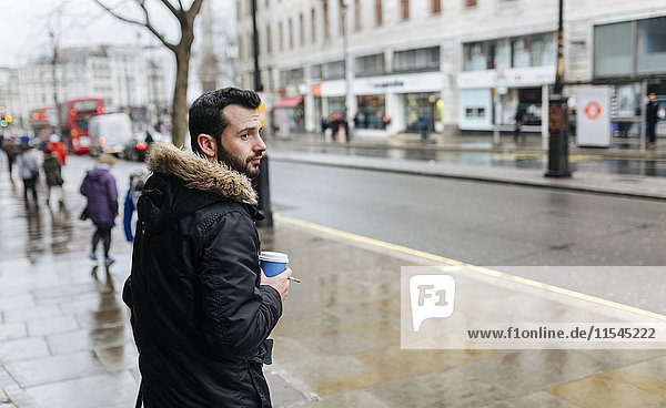 UK  London  Mann mit Kaffee für einen verregneten Tag