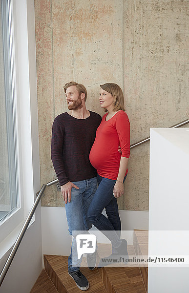 Lächelnder Mann und schwangere Frau auf der Treppe stehend