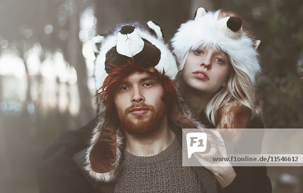 Porträt eines jungen Paares mit Tierhüten im Wald