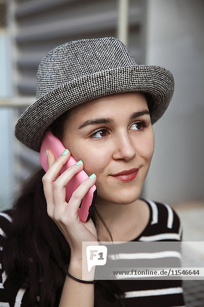 Portrait einer jungen Frau beim Telefonieren mit dem Smartphone