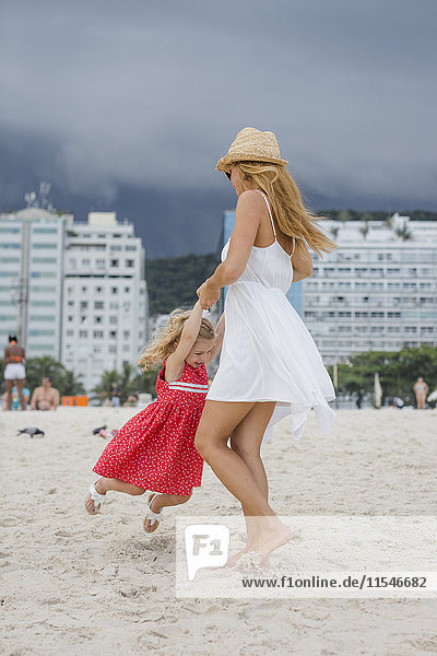 Brasilien  Rio de Janeiro  Mutter und Tochter spielen am Strand von Copacabana