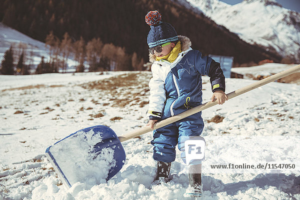 Italy  Val Venosta  Slingia  small boy using a large snow shovel