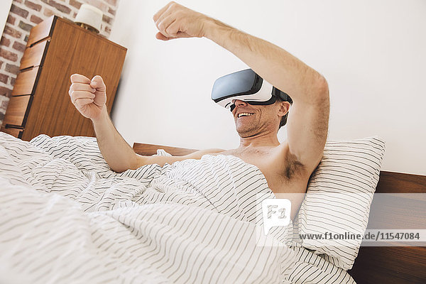 Man in bed wearing virtual reality glasses steering