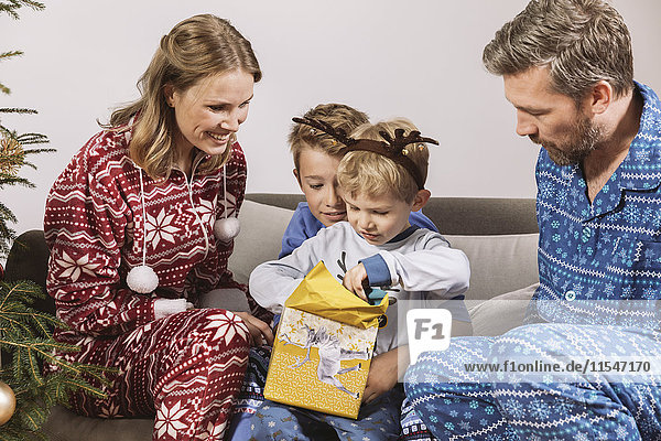 Eltern beobachten Sohn beim Auspacken eines Weihnachtsgeschenks