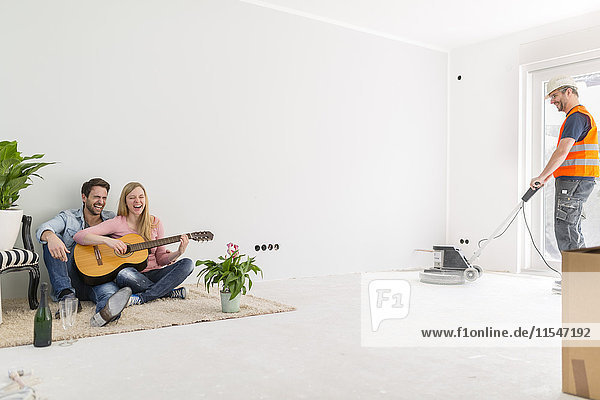 Ein glückliches Paar spielt Gitarre und singt in ihrem neuen Zuhause.