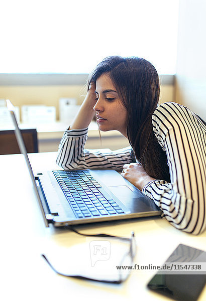 Geschäftsfrau an ihrem Schreibtisch mit Blick auf den Laptop