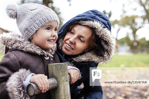 Porträt eines glücklichen kleinen Mädchens mit ihrer Mutter auf einem Spielplatz im Herbst