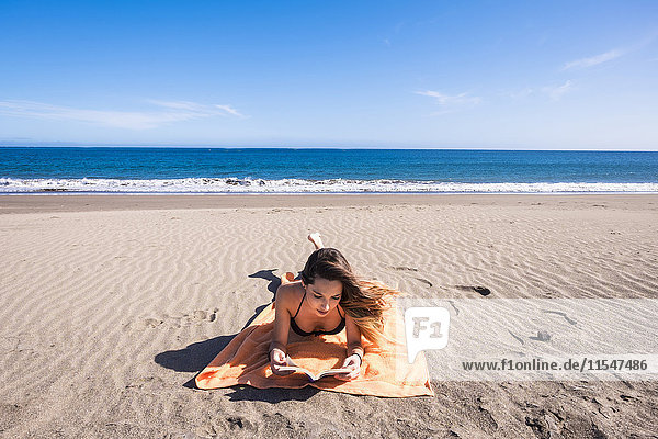Spanien  Teneriffa  junge Frau beim Lesen am Strand