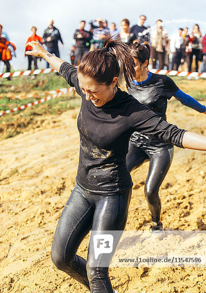 Participants in extreme obstacle race  running through mud