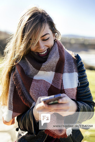 Lächelnde junge Frau mit Smartphone im Freien