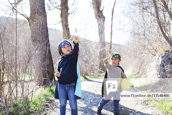 Two little boys dressed up as a superheros posing on a path
