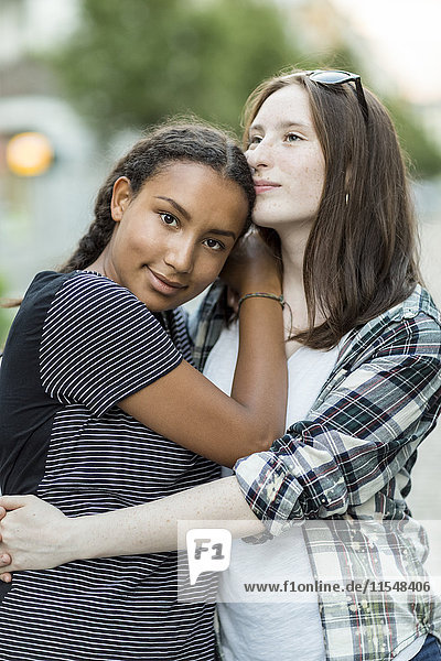 Two teenage girls hugging outdoors