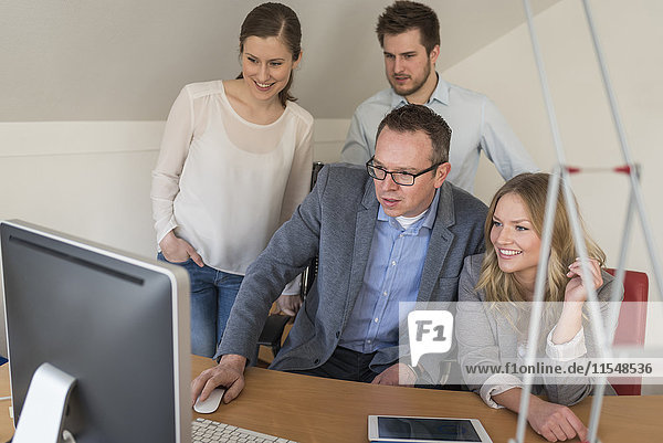Vier Kollegen im Büro beim Blick auf den Computerbildschirm