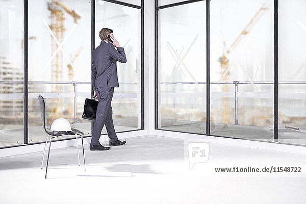 Businessman talking on phone in office under construction