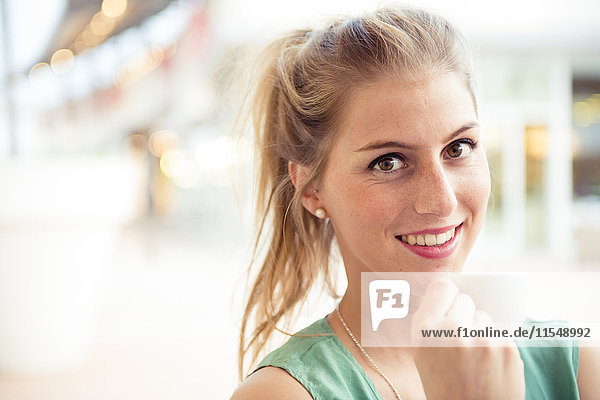 Porträt einer lächelnden blonden Frau im Outdoor-Café