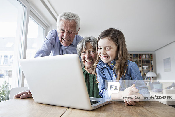 Die Großeltern und ihre Enkelin haben Spaß mit dem Laptop zu Hause.