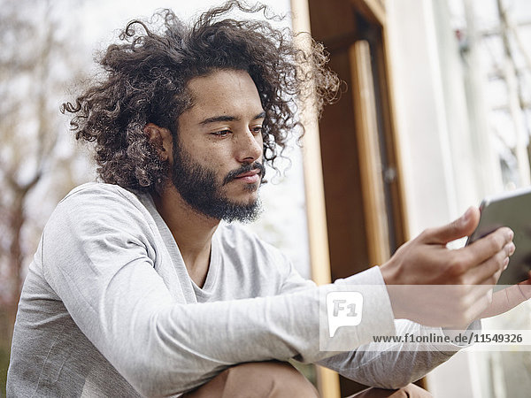 Junger Mann beim Betrachten des digitalen Tabletts im Freien