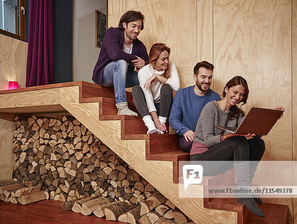 Freunde sitzen auf Holztreppe mit Laptop