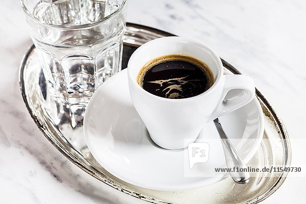 Tasse Espresso und Glas Wasser auf Metallplatte