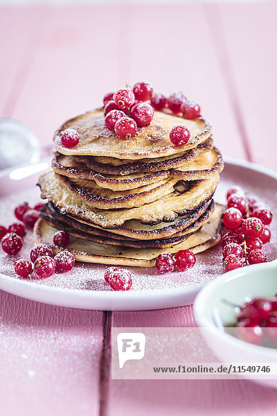 Stack of American pancakes with red currents sprinkled with icing sugar