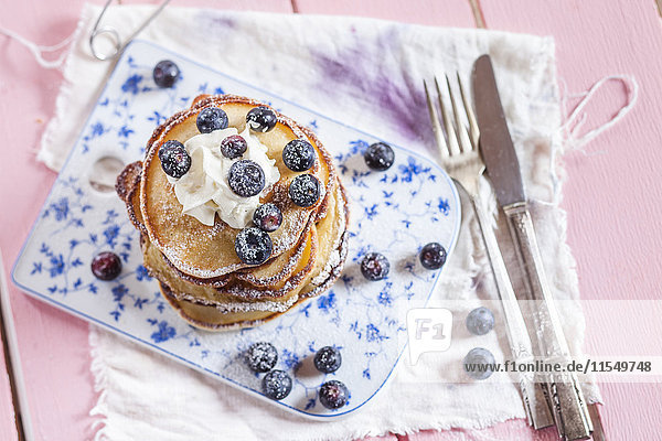 Stack of American pancakes with whipped cream and blueberries