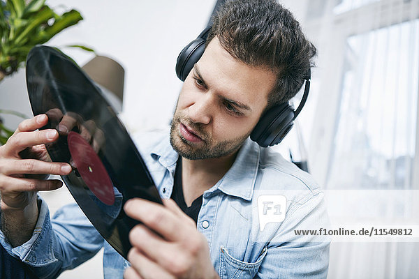 Young man wearing headphones looking at record