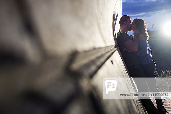 Couple in love kissing at a wall