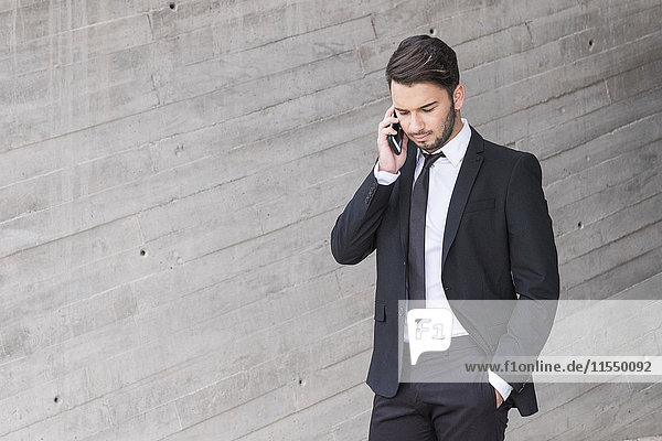 Geschäftsmann im schwarzen Anzug telefoniert mit Smartphone