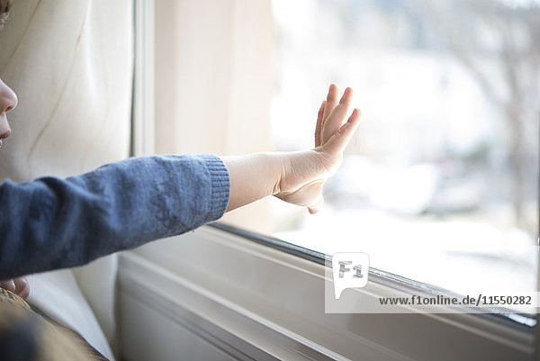 Hand des kleinen Jungen beim Berühren der Fensterscheibe