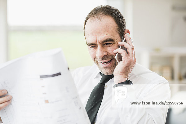 Businessman holding plan and talking on cell phone