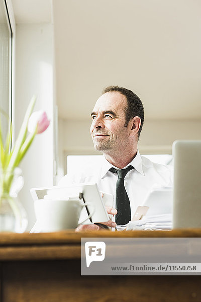 Confident businessman at wooden table thinking