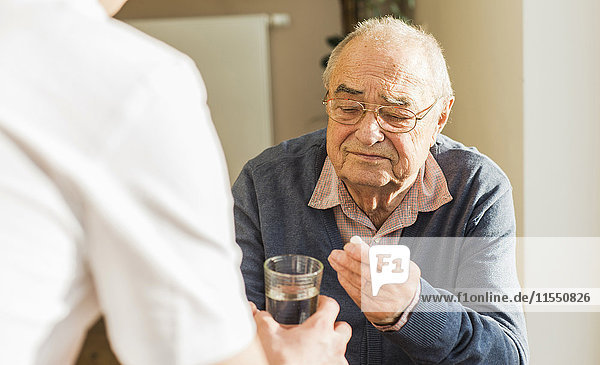 Älterer Mann bekommt Tablette und Glas Wasser