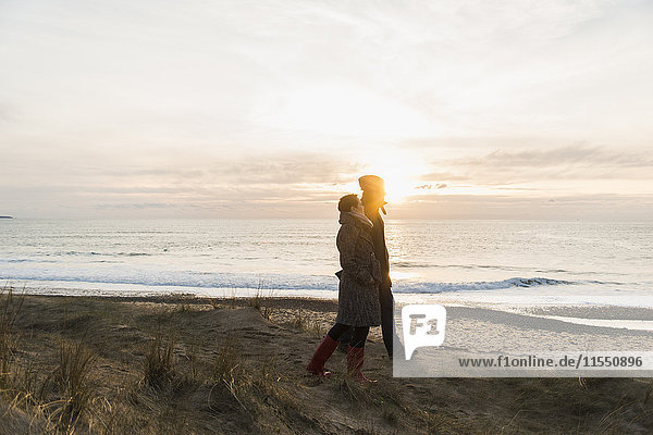 Frankreich  Bretagne  Finistere  Halbinsel Crozon  Paar bei Sonnenuntergang an der Küste spazieren gehen