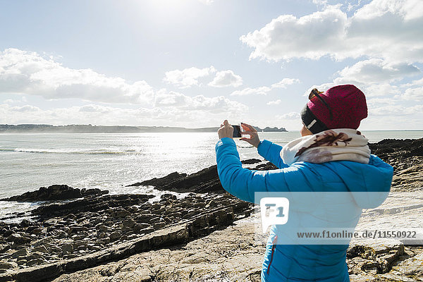 Frankreich  Bretagne  Finistere  Halbinsel Crozon  Frau an der Felsenküste beim Fotografieren