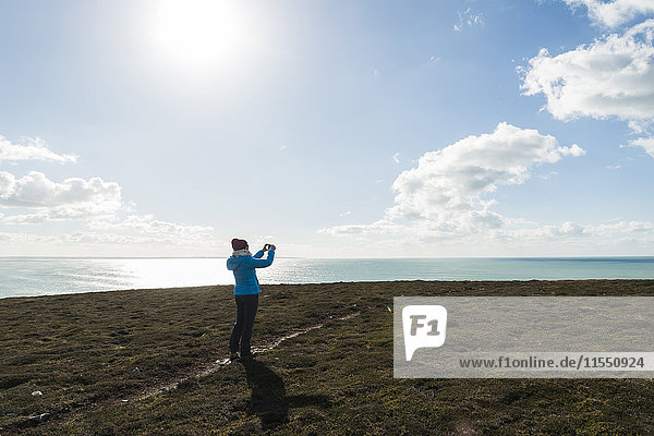 Frankreich  Bretagne  Finistere  Halbinsel Crozon  Frau steht an der Küste und fotografiert