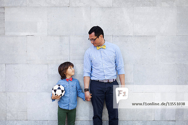 Father and son holding hands  boy holding soccer ball