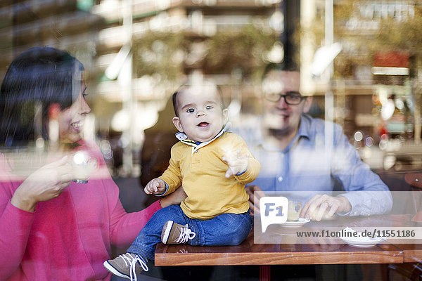 Junge sitzt auf dem Tisch in einem Café und schaut durch die Fensterscheibe.