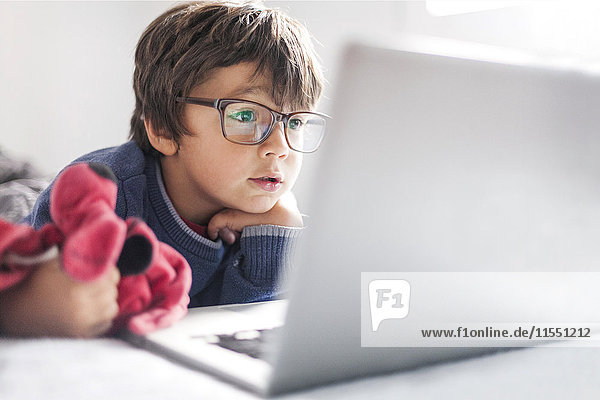 Portrait of little boy wearing oversized glasses looking at laptop