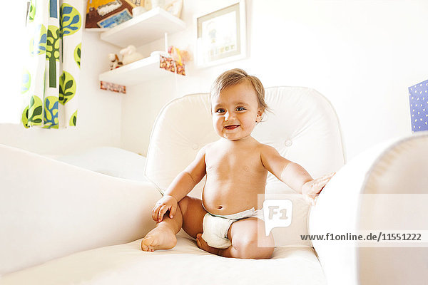 Smiling baby boy with diapers sitting on an armchair
