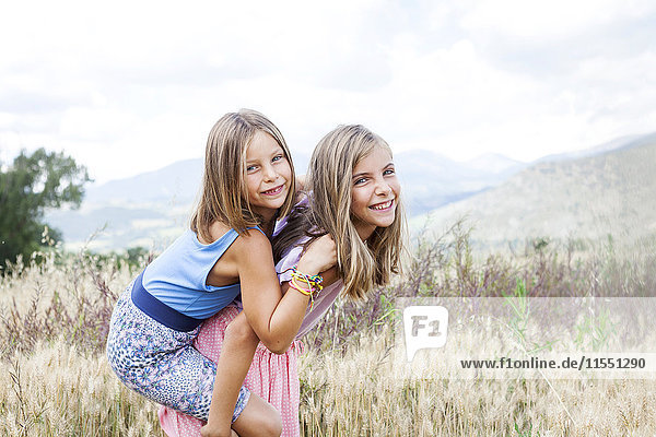 Spain  Girona  portrait of two happy sisters playing on a meadow