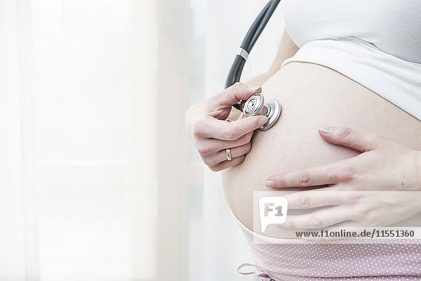 Schwangere Frau hält Stethoskop vor den Bauch